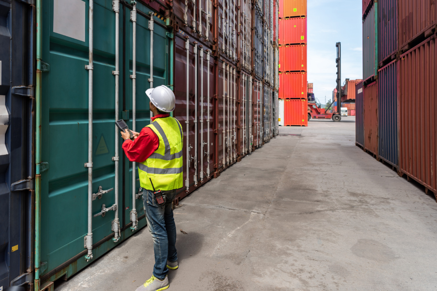 Alt text: A port worker is checking a green container.
