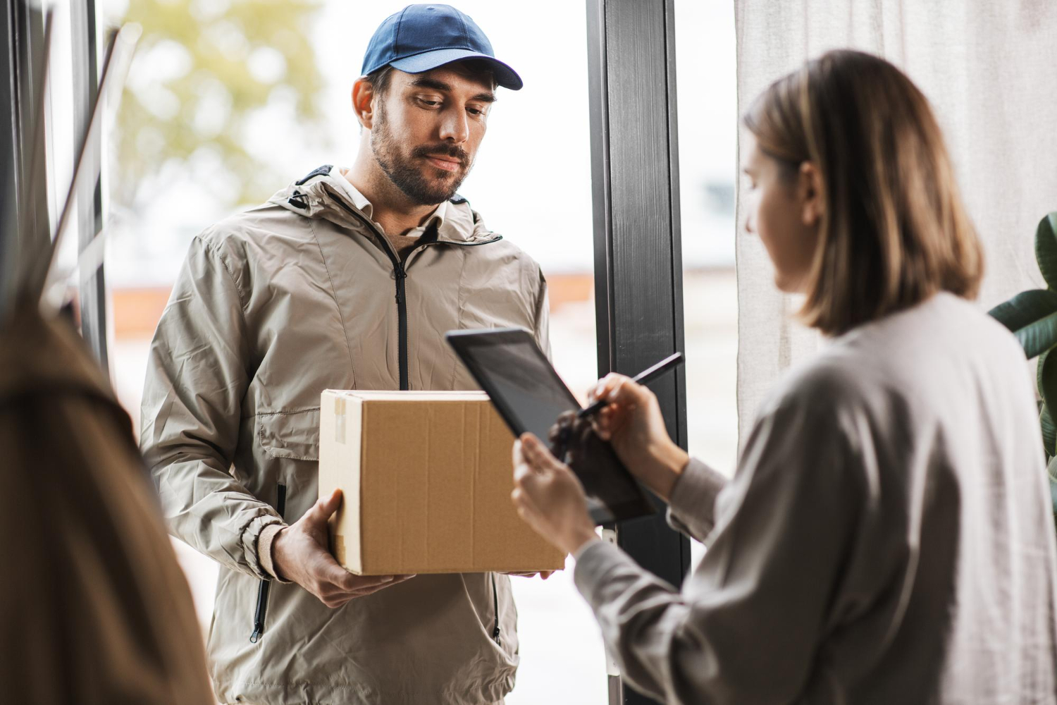 Alt text: Delivery man with box and woman signs digital form