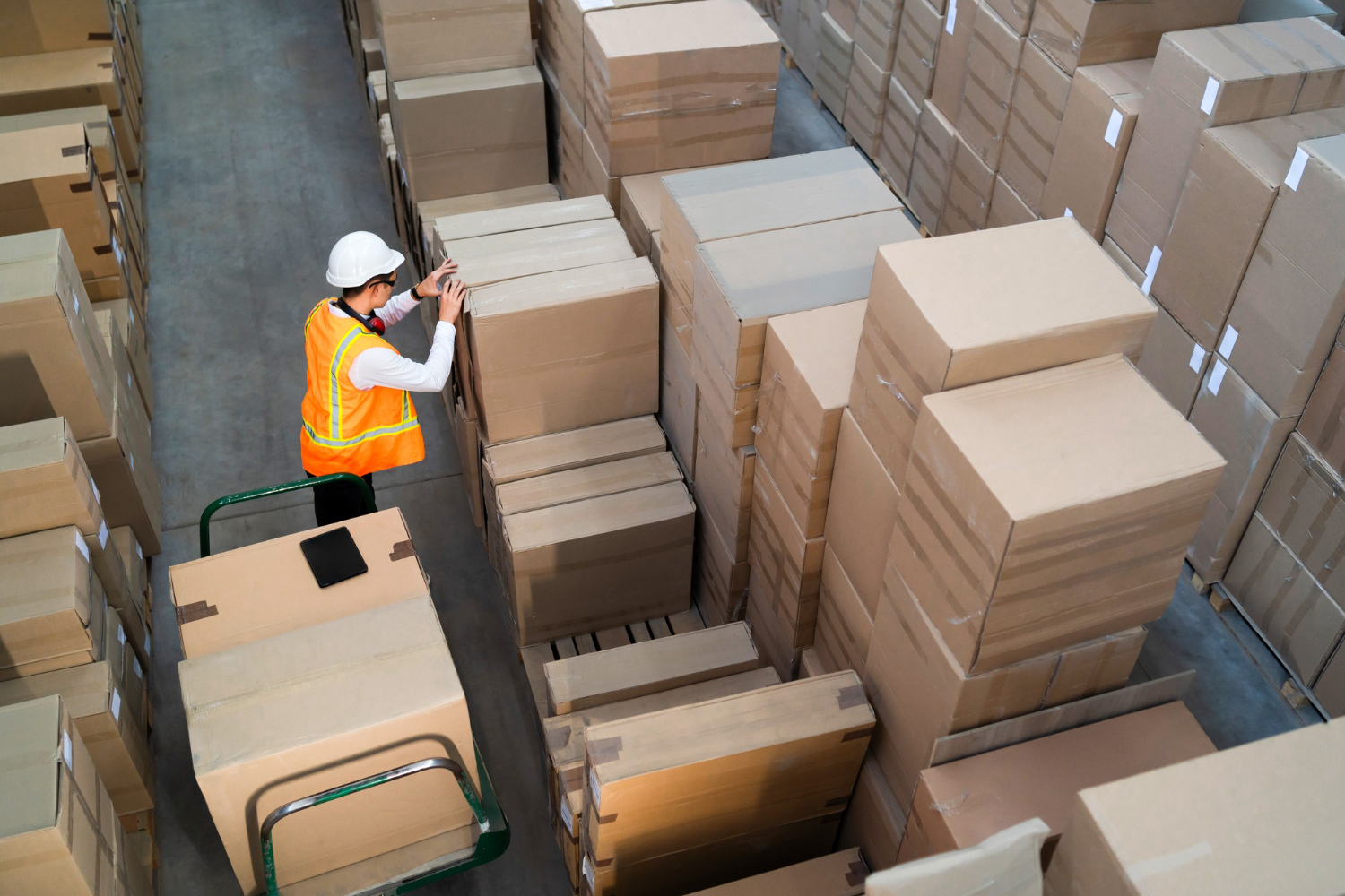 Alt text: A warehouse worker is checking boxes at a warehouse.