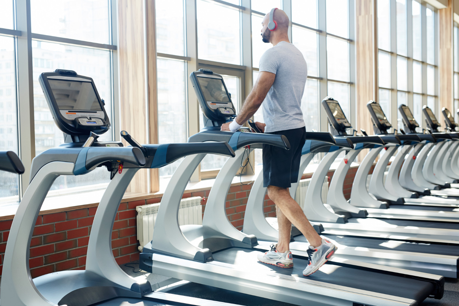 Alt text: A man with headphones is using a treadmill in a fitness centre.