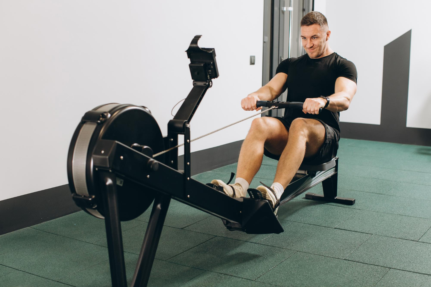 Alt text: A man is using a rowing machine during a workout.