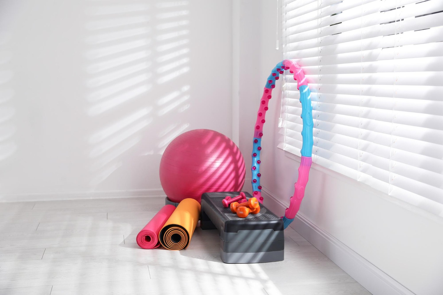 Alt text: Different sports equipment is placed near the window in a home gym.
