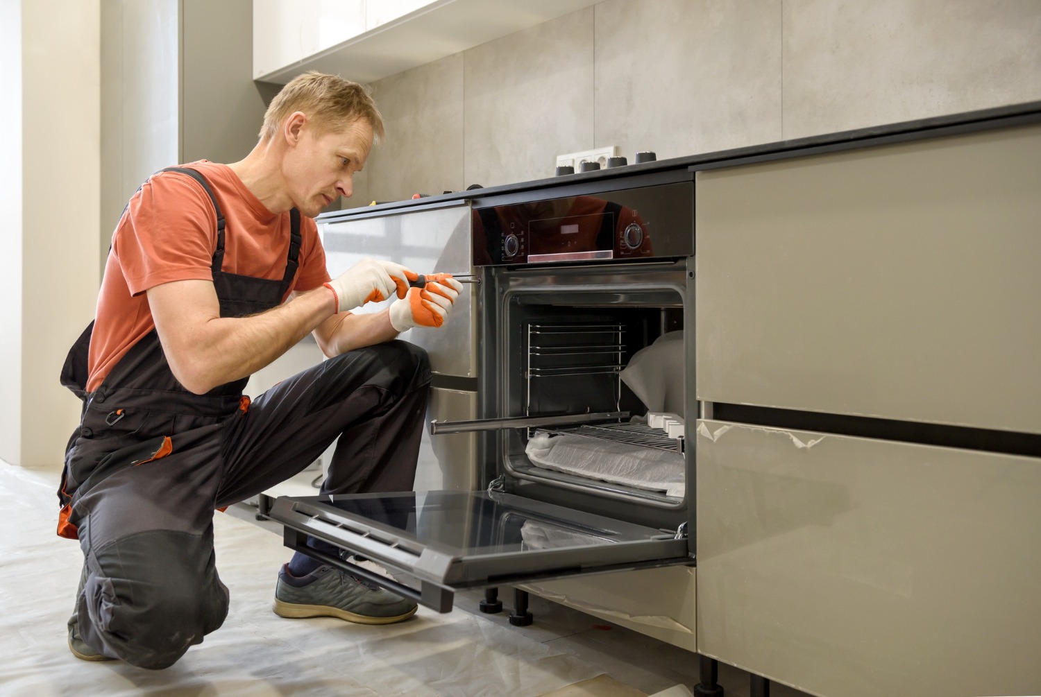 Alt text: A man is installing a brand new oven in a counterspace.