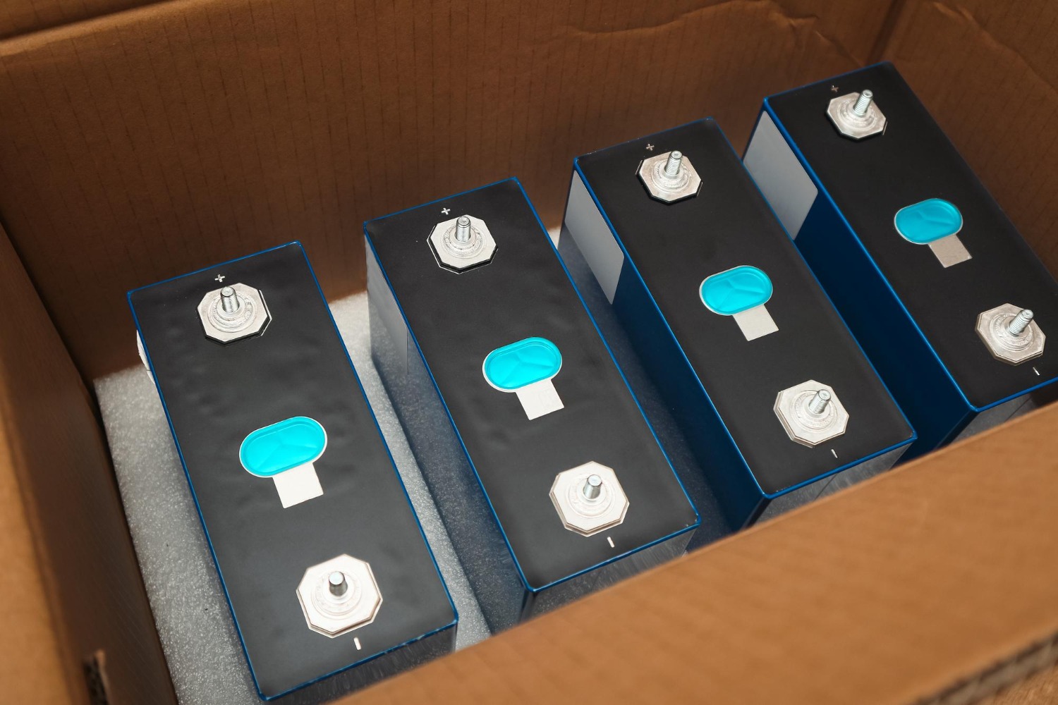 Alt text: Row of lifepo4 cells in cardboard box prismatic modules for lithium iron phosphate battery lithium iron phosphate lifepo4 blue prismatic cell.