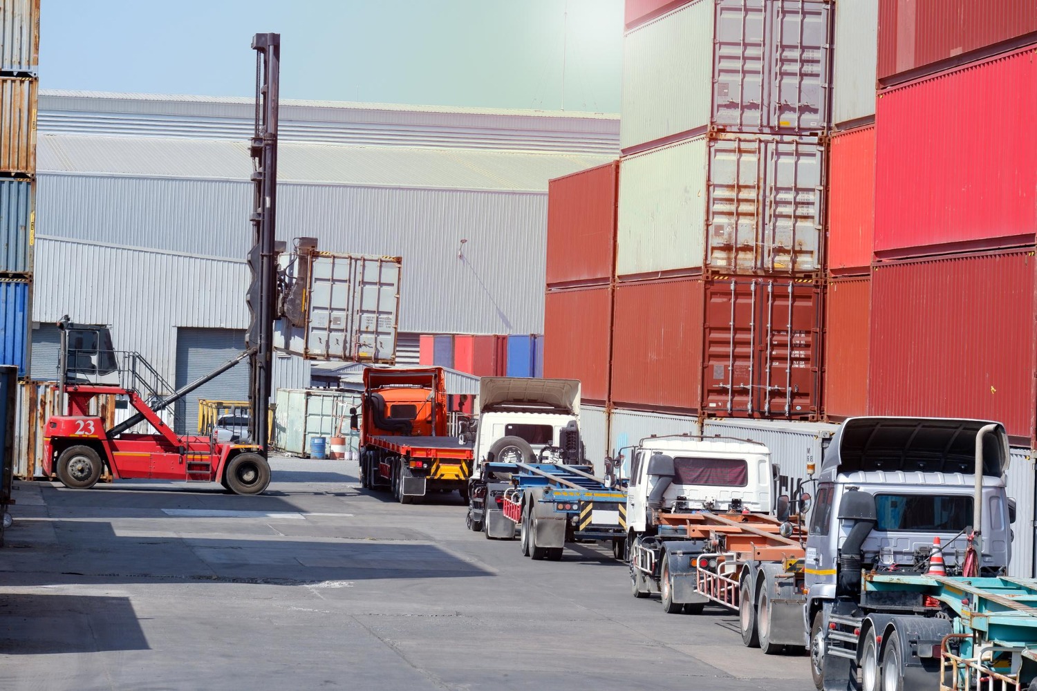 Alt text: Trucks and forklifts loading shipping containers at a busy Australian freight yard, preparing for international shipping.
