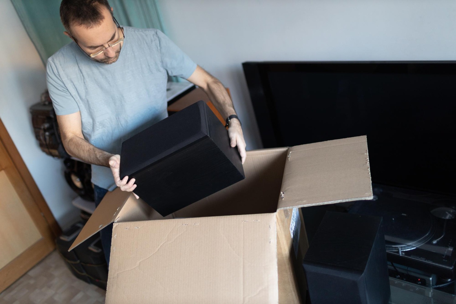 Alt text: A homeowner is unpacking a stereo set for a television.