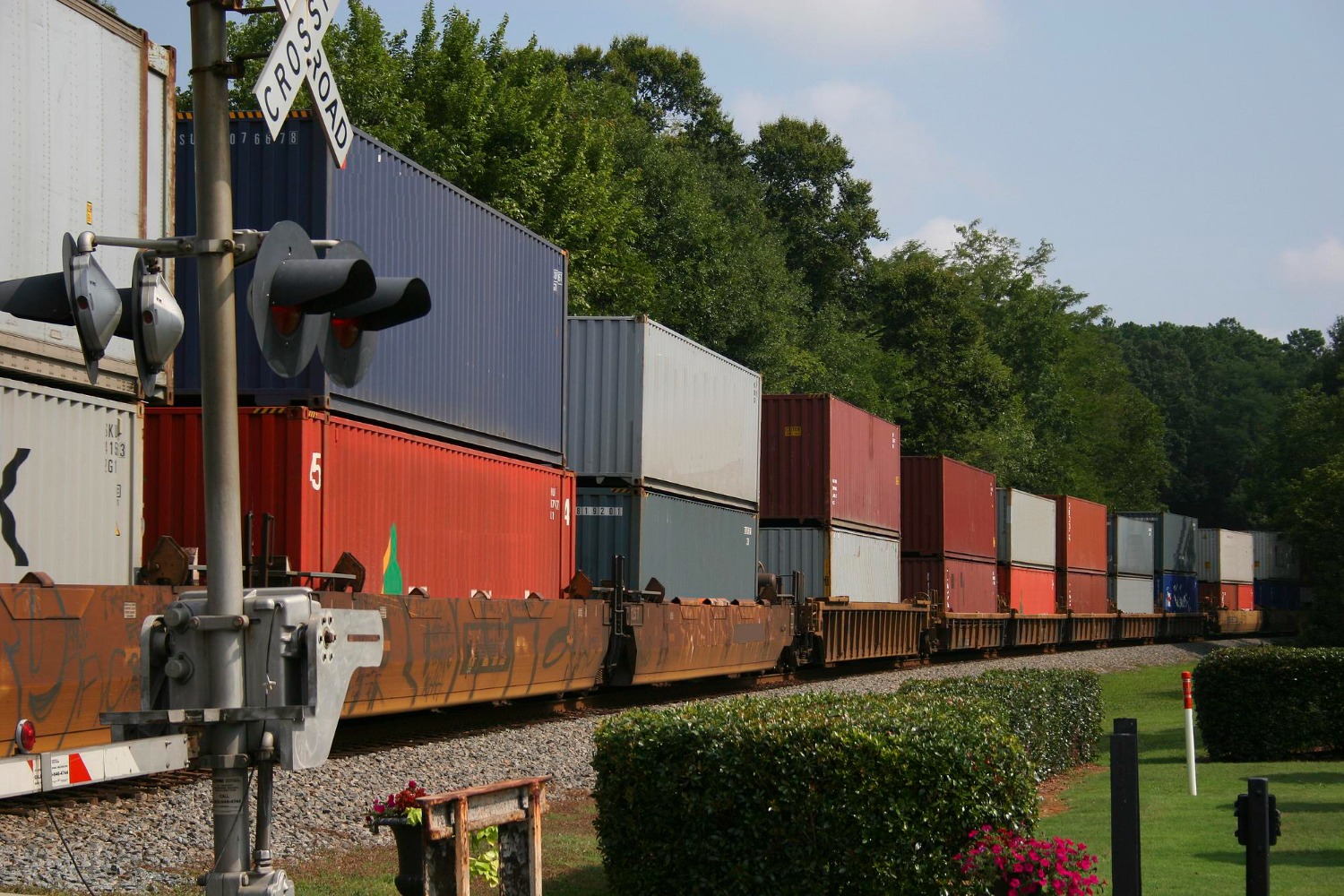 Alt text: Shipping containers are stacked on top of each other and are being transported via rail.