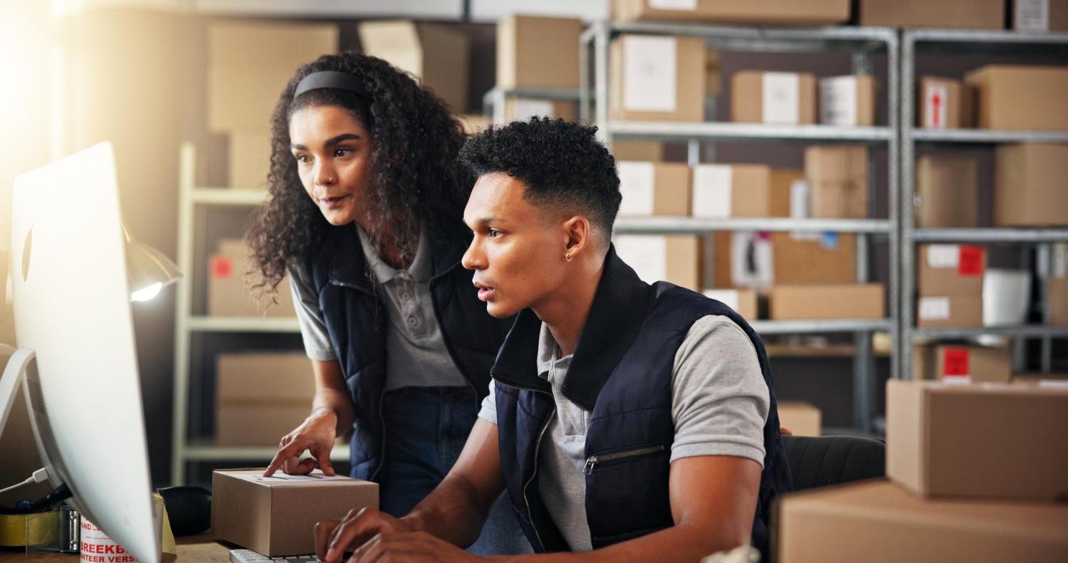Alt text: Two workers are checking the computer for stock and inventory