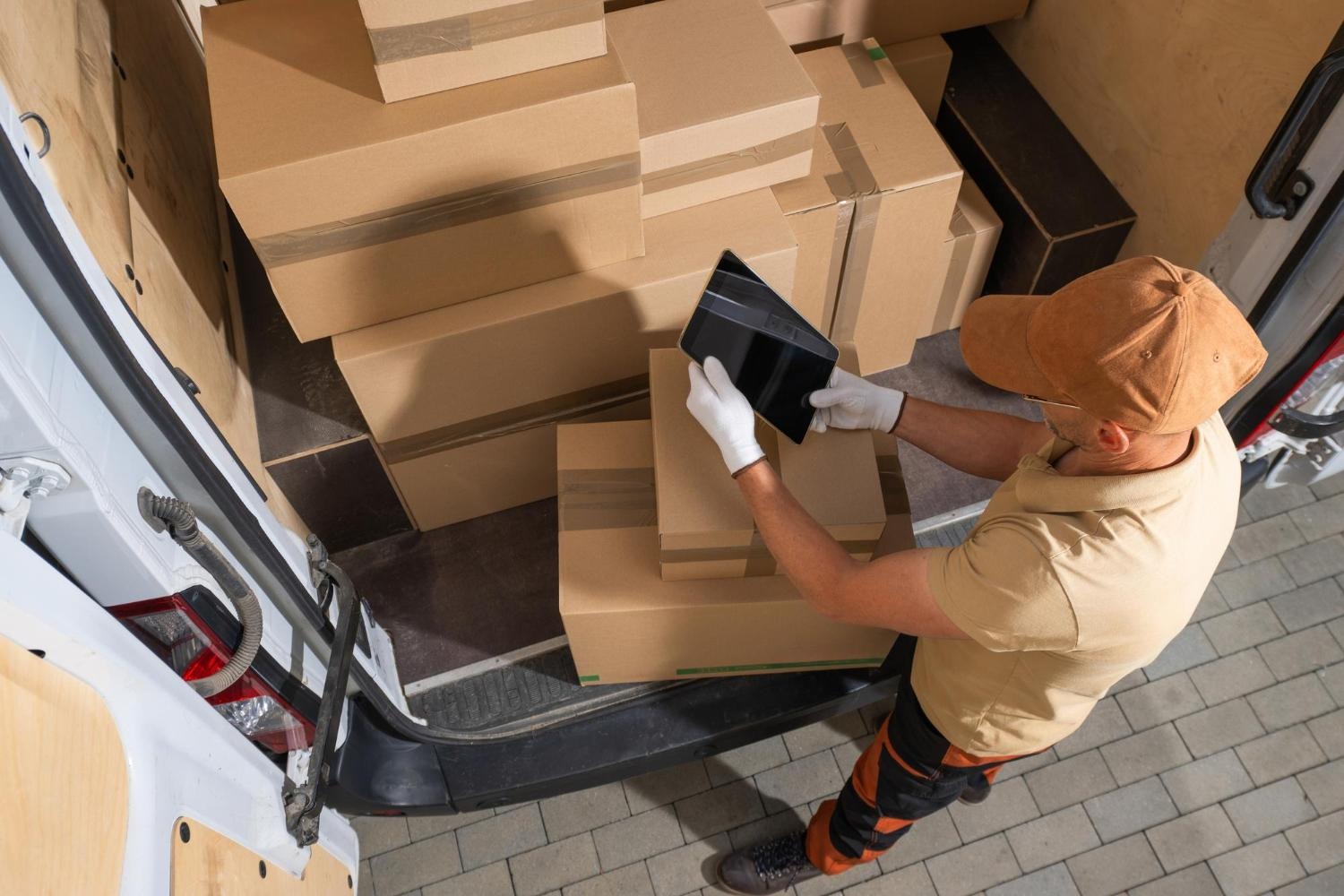 Alt text: A courier is checking their tablet while delivering packages.