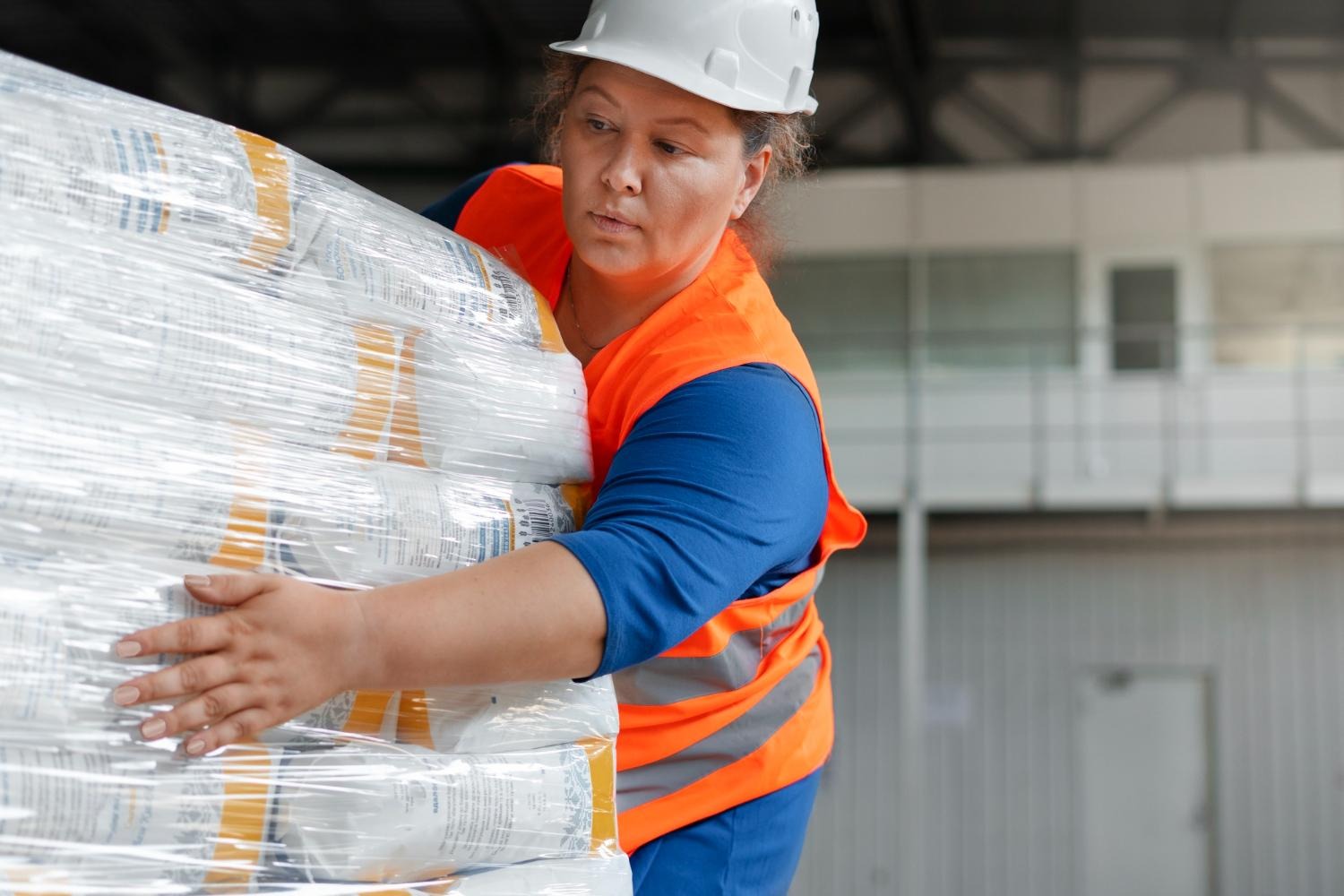 Alt text: A warehouse worker is securing a shipment with wrapping.