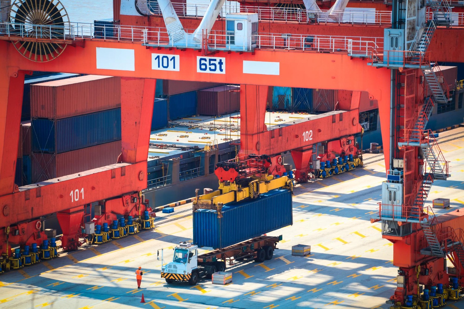 Alt text: Shipping container being transferred at a busy cargo terminal as freight operators manage international supply chain movements.