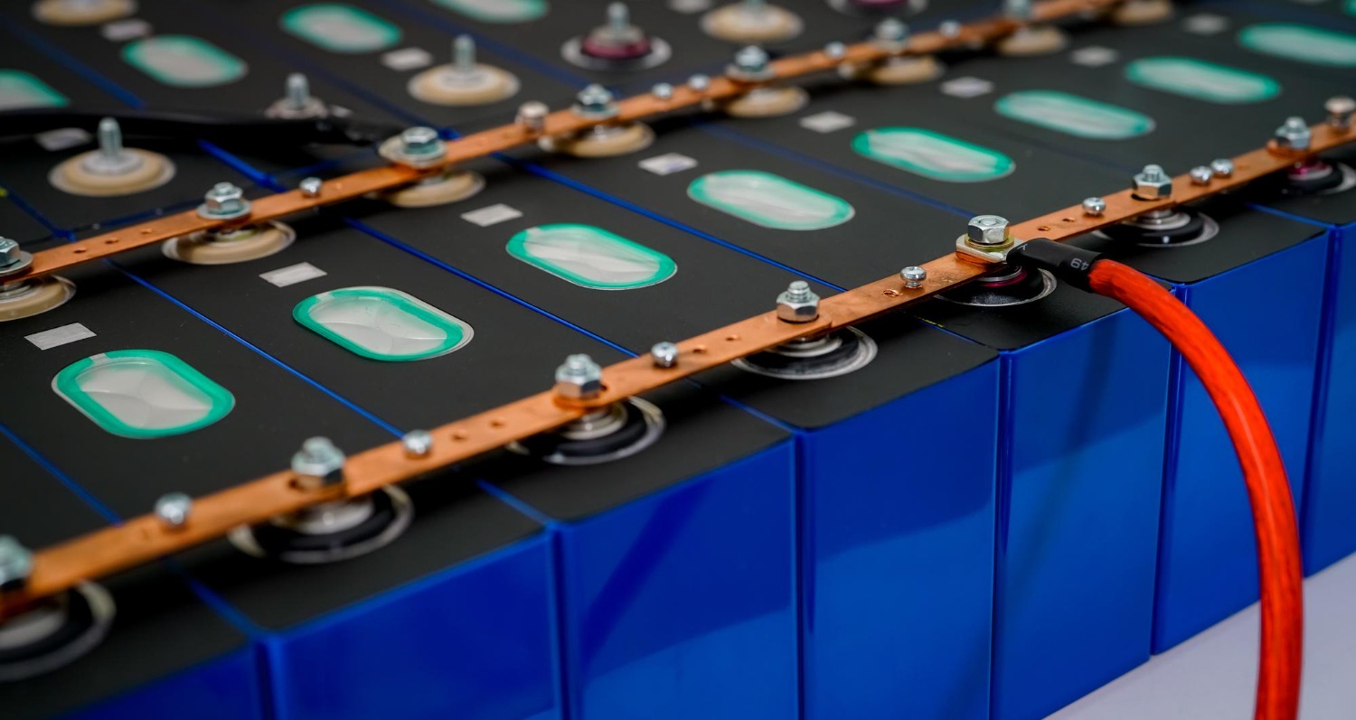 Alt text: Close-up of lithium-ion battery cells connected with copper busbars and power cables in an industrial battery pack system.