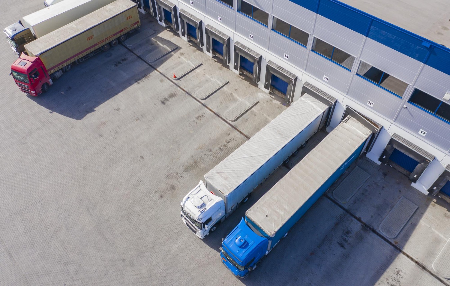 Alt text: Aerial view of freight trucks docked at a warehouse distribution centre for interstate linehaul shipping.