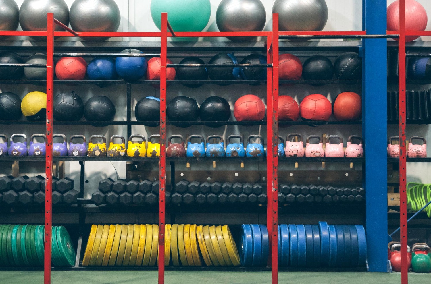 Alt text: Shelving unit stocked with fitness equipment in a gym or fitness warehouse setting.