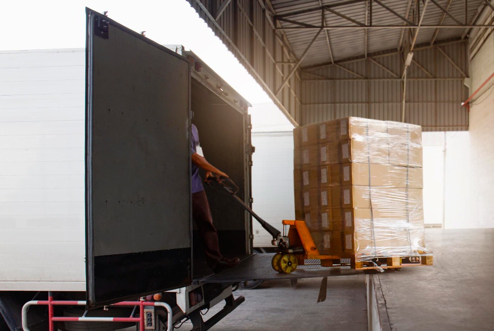 Alt text: Worker loading package boxes into cargo container delivery