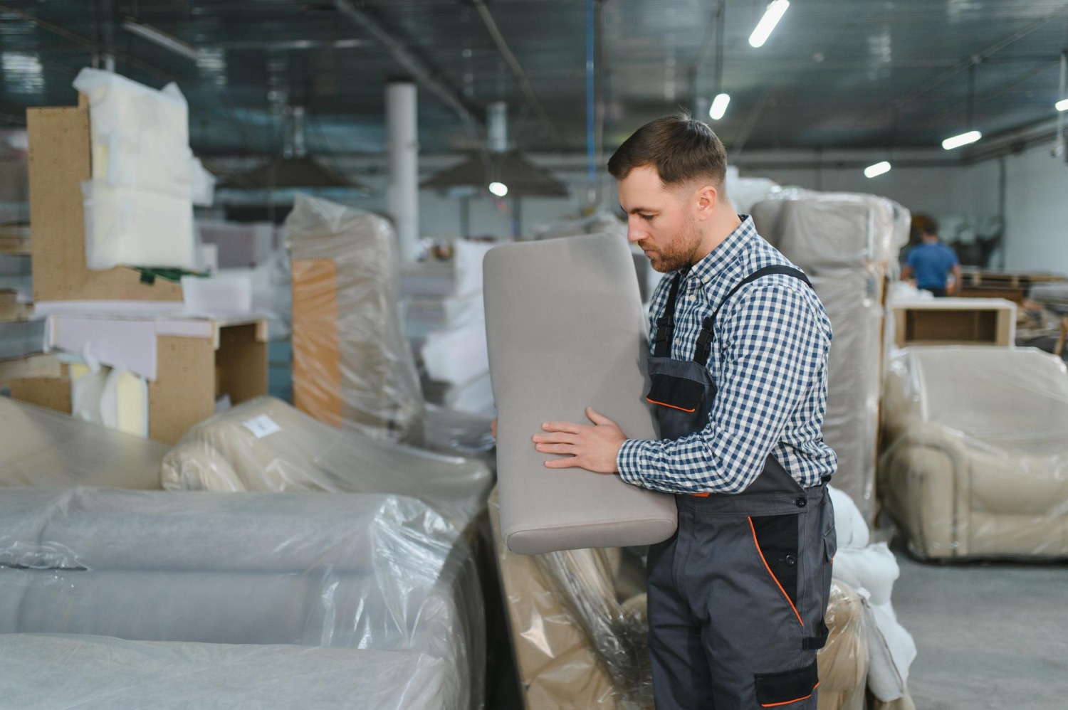 Alt text: Furniture inspector examining upholstered furniture in a manufacturing warehouse before shipment from China to Australia.