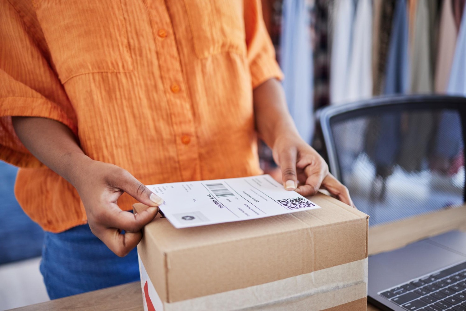 Alt text: Person applying a shipping label to a parcel before preparing an international shipment.