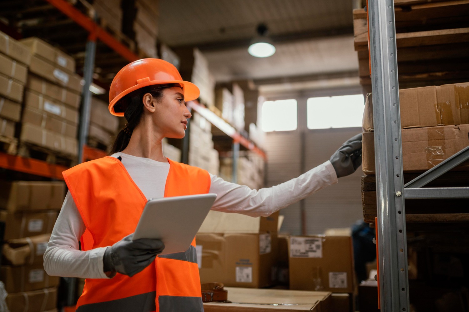 Alt text: Warehouse worker inspecting pallet inventory in a fulfilment warehouse using a tablet.