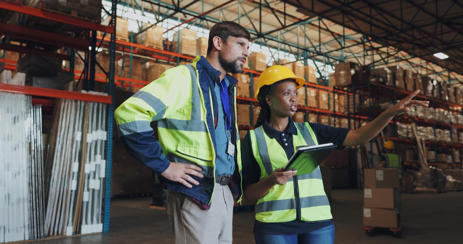 Alt text: Warehouse staff reviewing inventory and shipment planning using a tablet before dispatching stock to an Amazon fulfilment centre.
