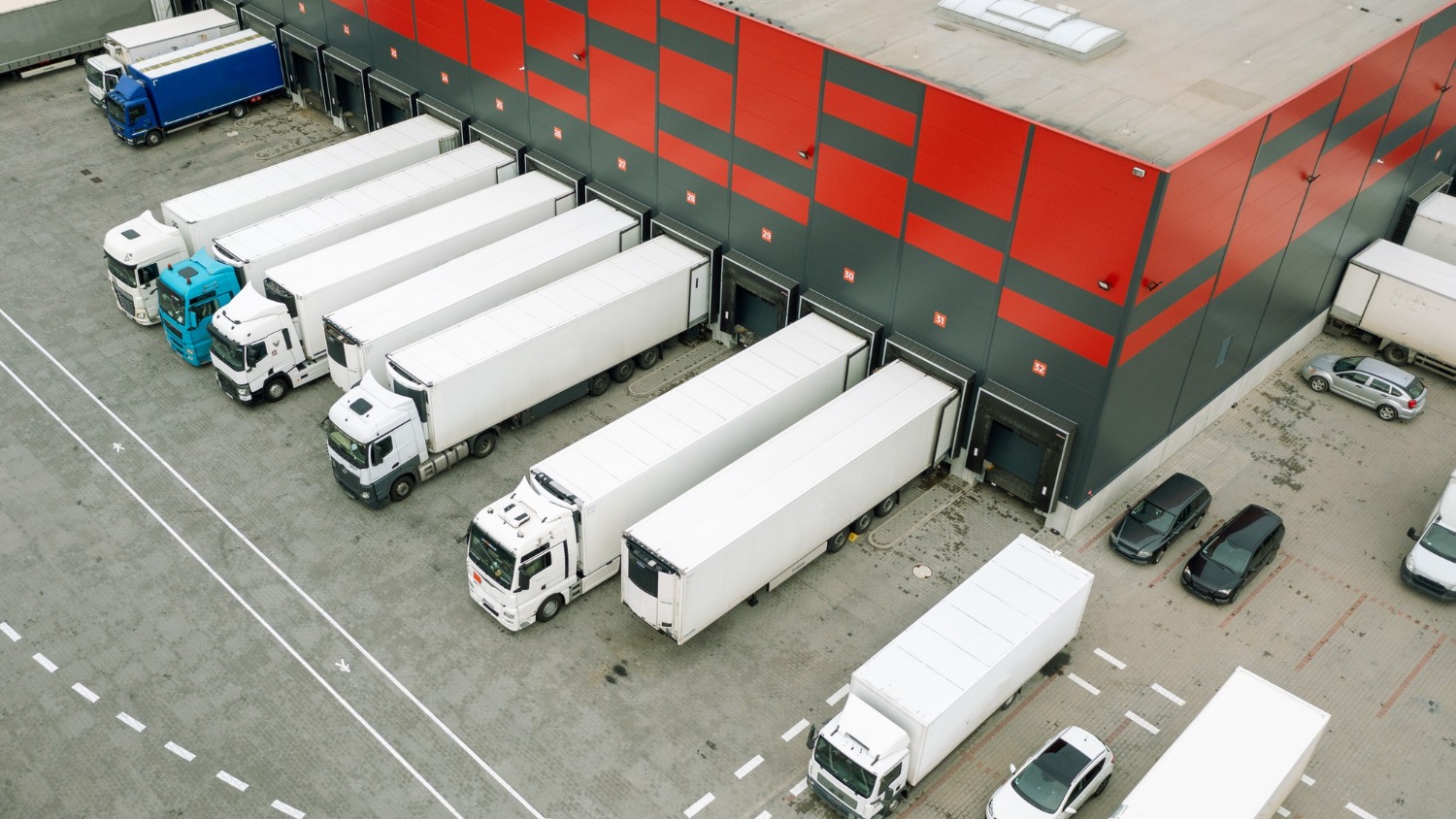 Alt text: Freight trucks loading at a logistics warehouse before road transport across Australia.