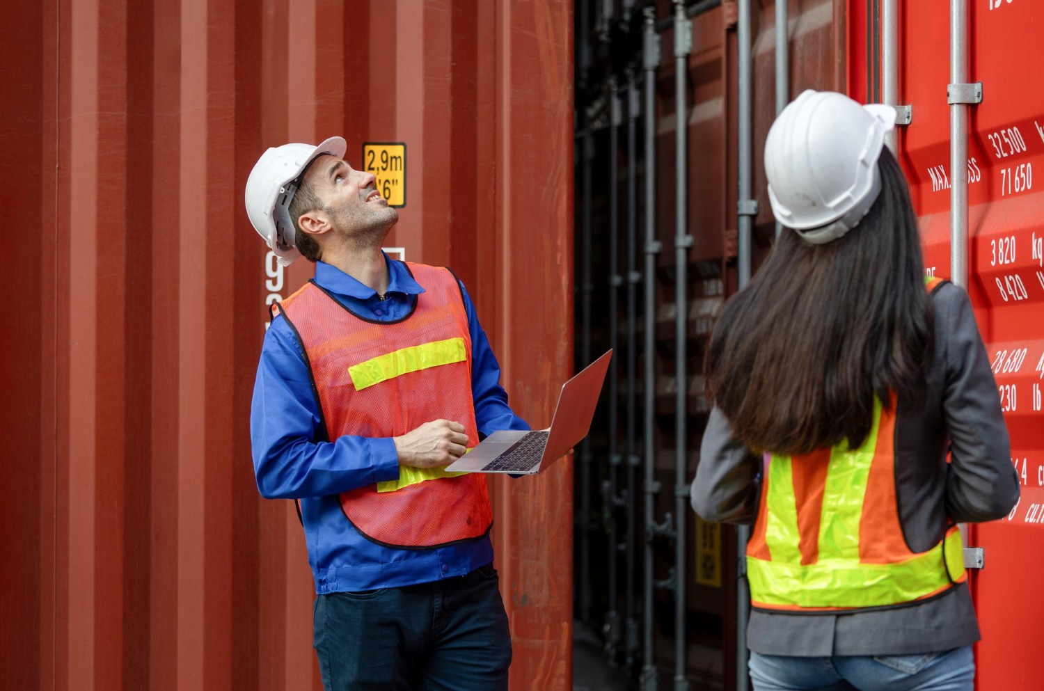 Alt text: Two logistics workers inspecting a shipping container at a cargo facility.