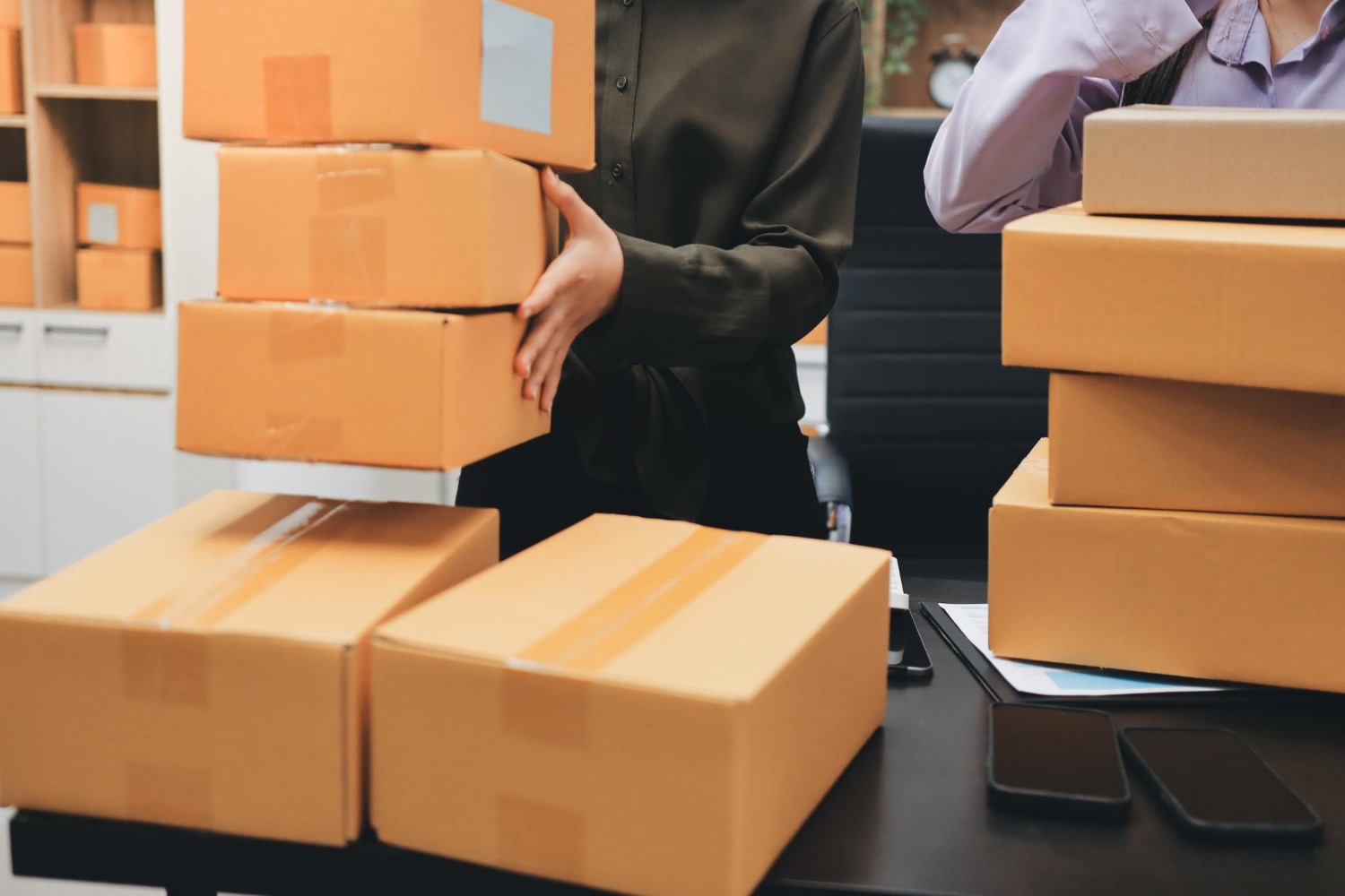 Alt text: Employees handling and packing cardboard boxes for shipment.