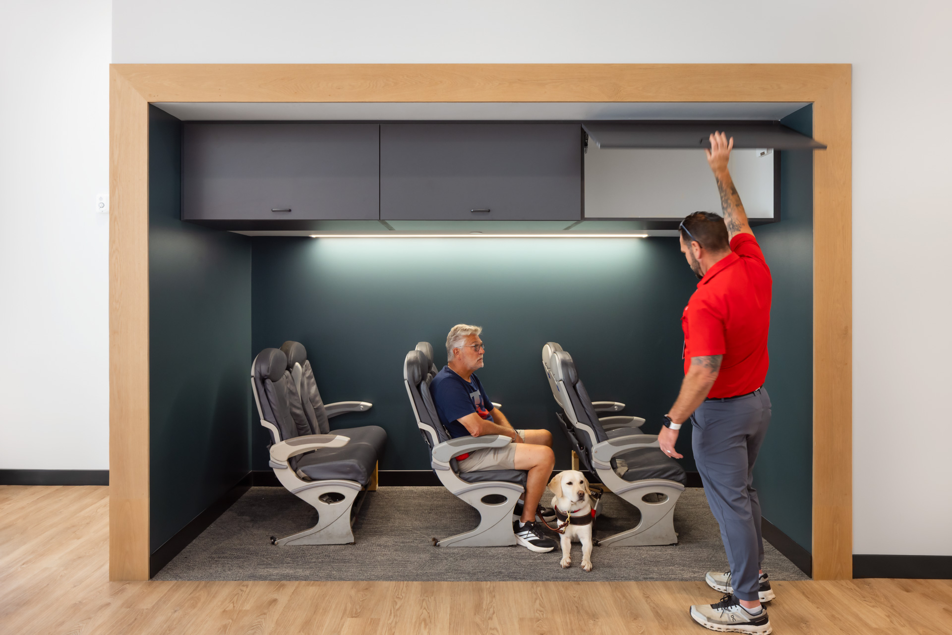 Airplane simulation training area at Pilot Dogs with airline-style seating as a student and guide dog practice with an instructor