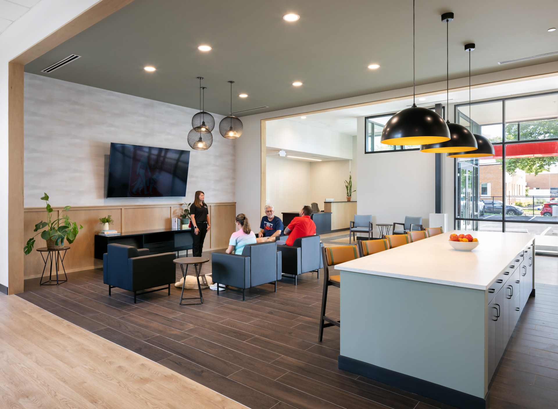 Pilot Dogs front lobby lounge with a large kitchen island, seating areas, and students gathered with guide dogs.