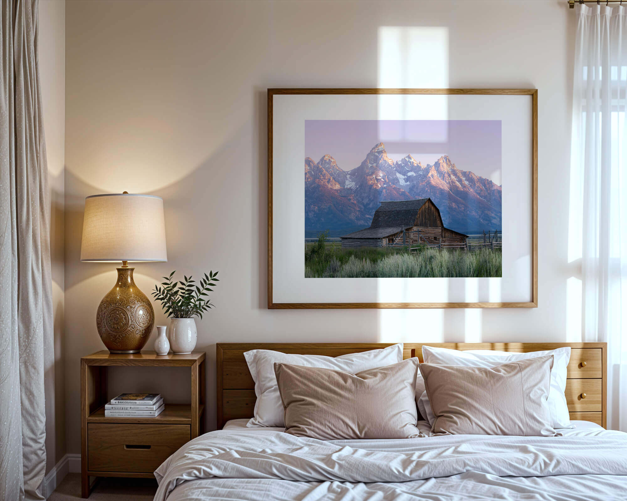 A framed photo of a barn in Grand Teton National Park over a bed