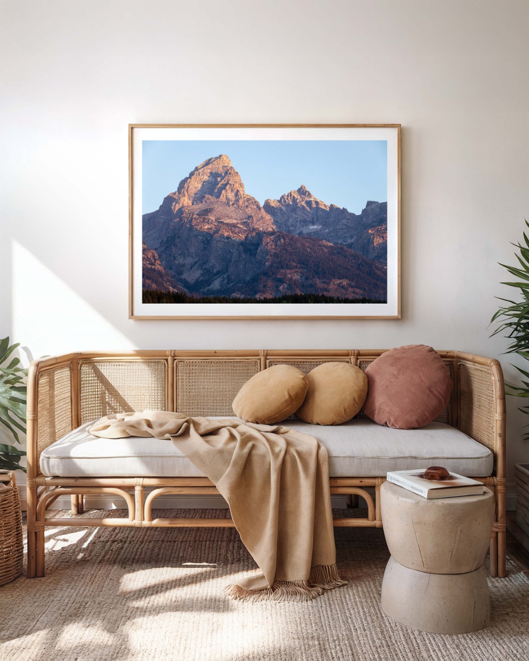 A framed photo of the Grand Teton mountain peak at sunrise hanging on a wall above a sofa