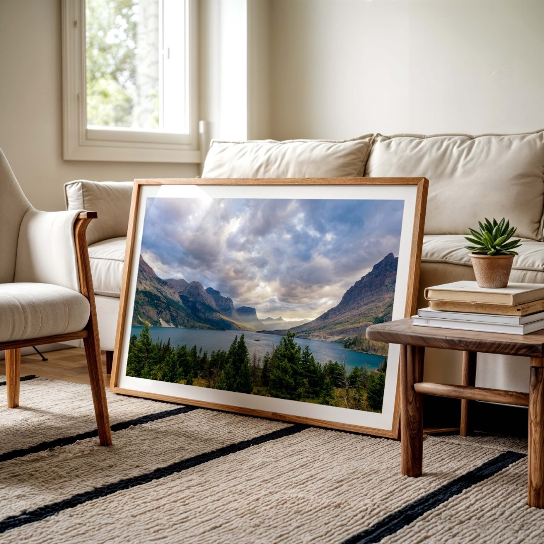 A framed photo of a sunset in Glacier National Park leaning against a couch on the floor