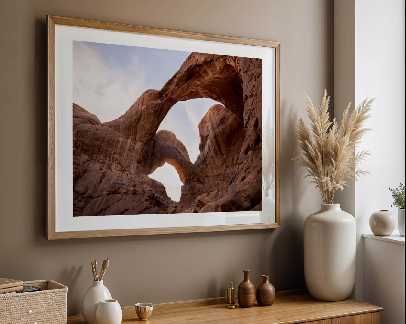 A framed photo of Double Arch in Arches National Park hanging on a wall above a piece of furniture