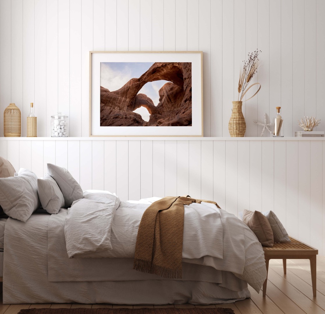A framed photo of Double Arch in Arches National Park hanging on a small ledge of a bedroom wall