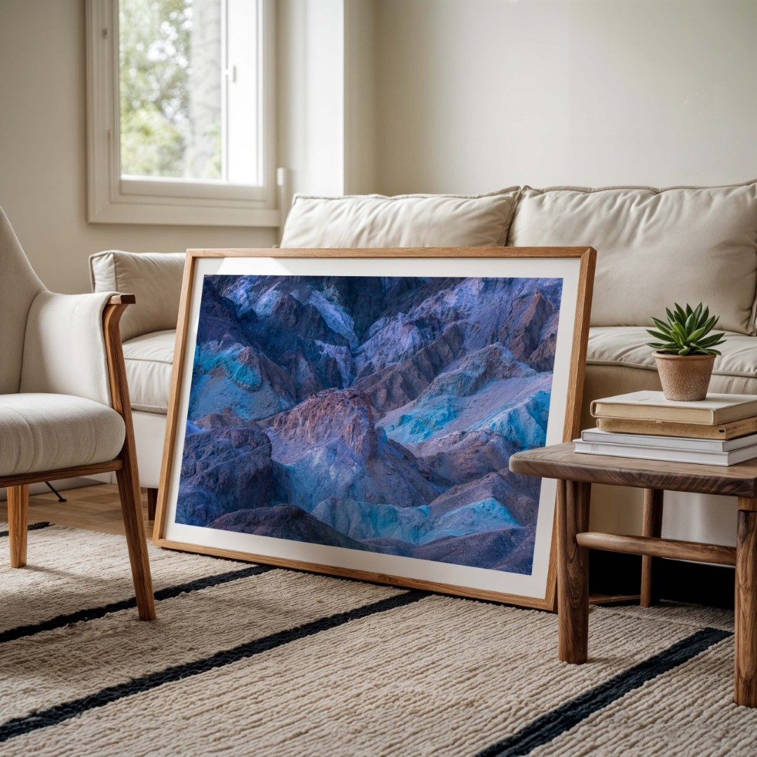 A framed photo of colorful rocky hills in Death Valley leaning against a couch on the floor