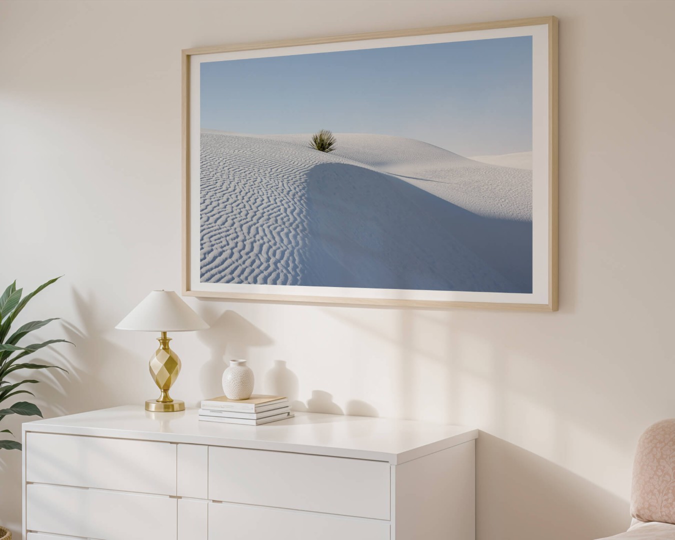 A framed photo of a single yucca plant in White Sands National Park hanging on a wall above a dresser