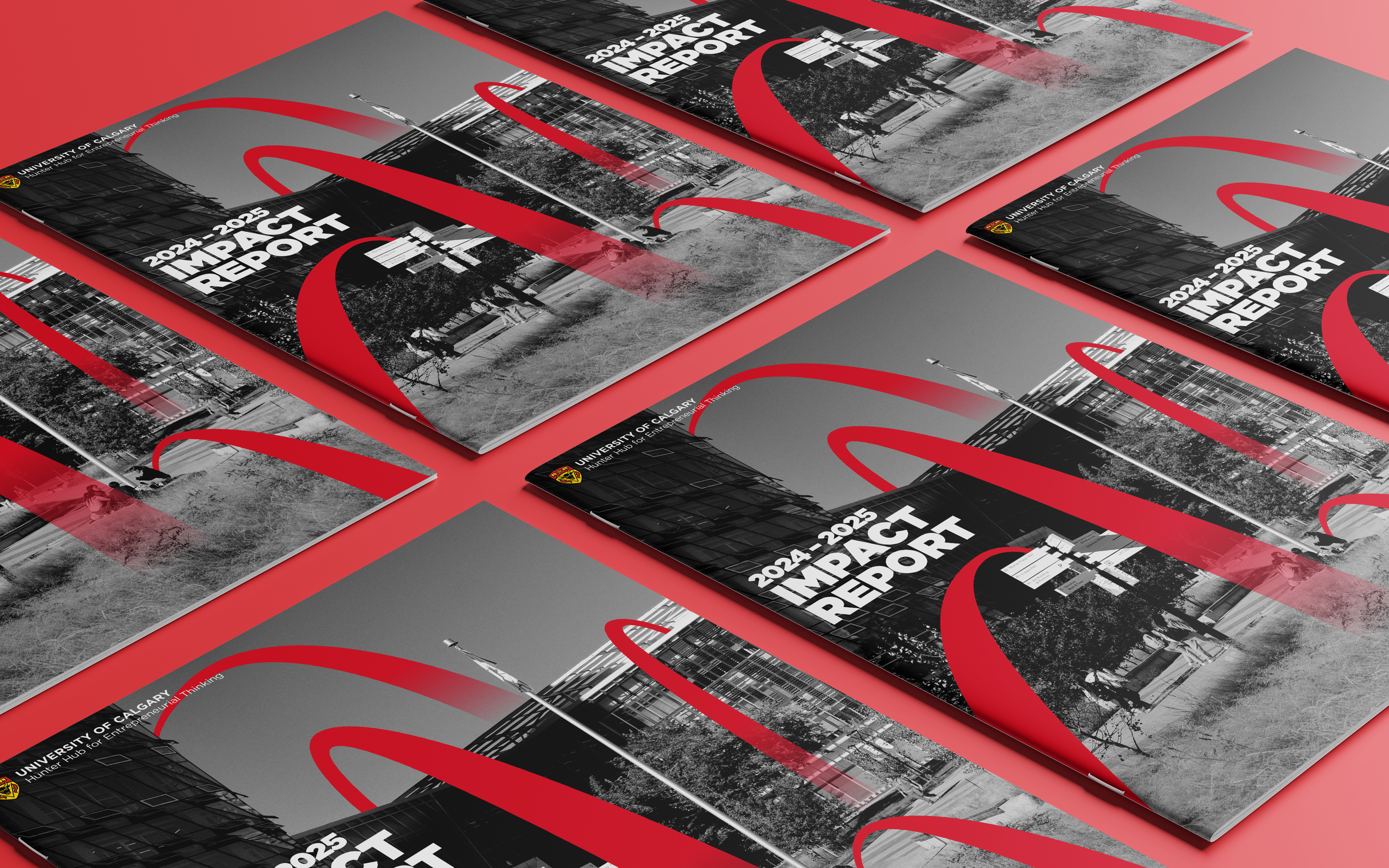 Multiple copies of the University of Calgary 2024-2025 Impact Report with a black and white campus photo and red design elements, displayed on a red surface.