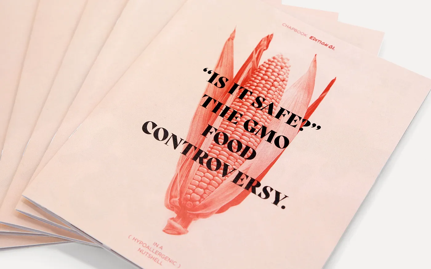 A stack of Simpson Centre GMO chapbooks titled 'Is it safe? The GMO food controversy' featuring an image of an ear of corn with its husk partially peeled back.