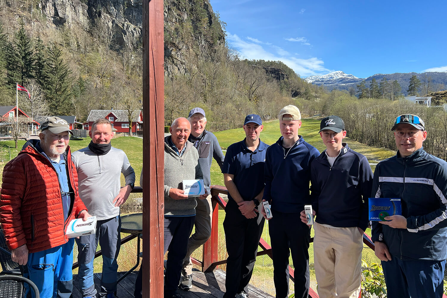Gruppe golfere oppstilt på terrasse ed bane i bakgrunn.