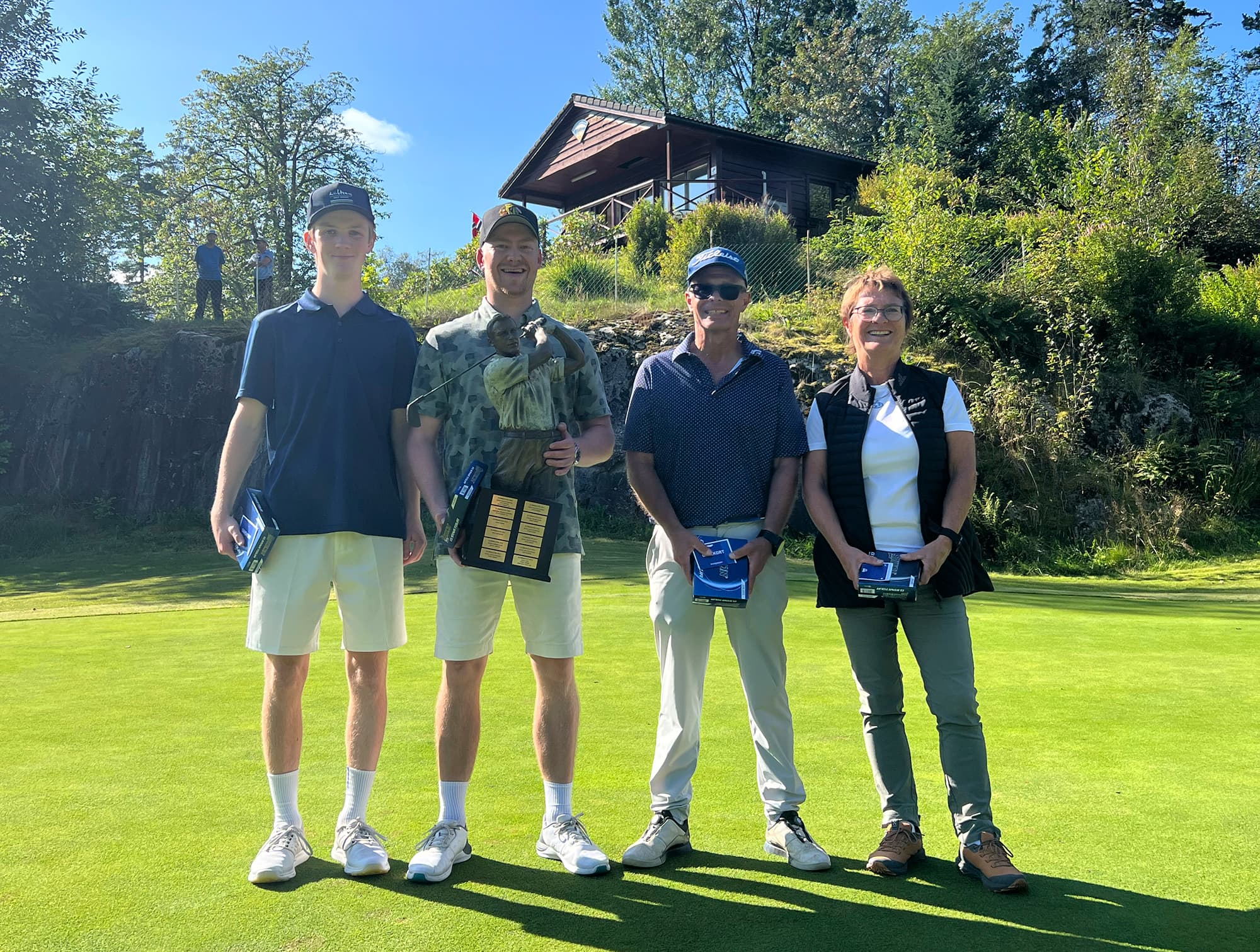 Golfere oppstilt på green med trofé.