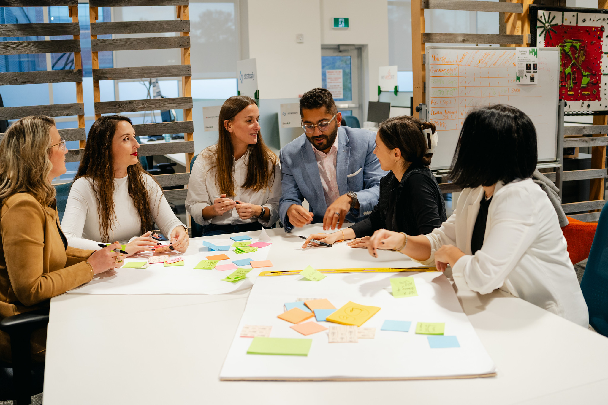Team collaborating around a table with sticky notes during a workshop.