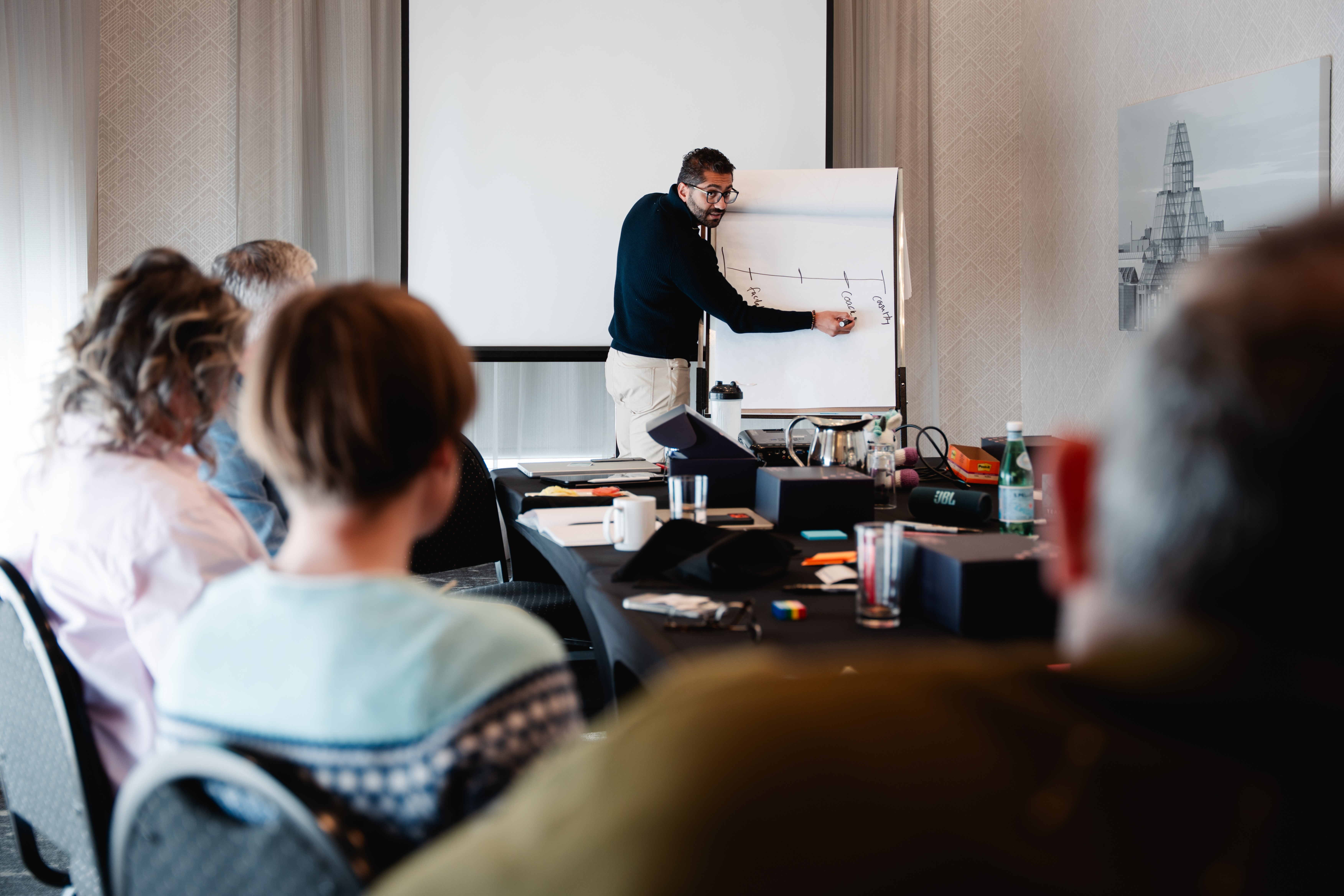 Fahd writing on flip chart, audience in foreground