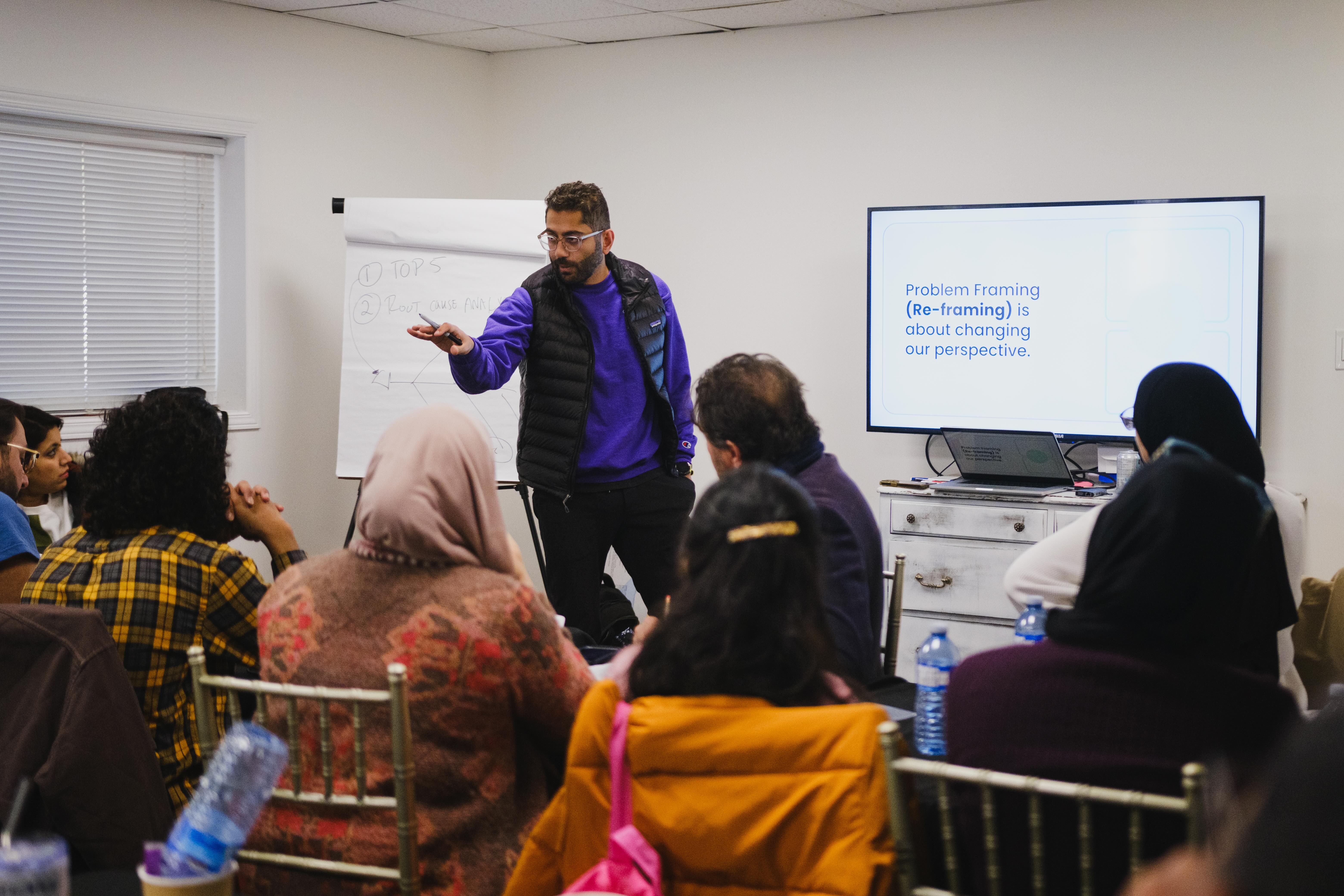 Fahd Alhattab of Unicorn Labs facilitating a leadership workshop on problem framing and reframing, presenting to an engaged in-person audience
