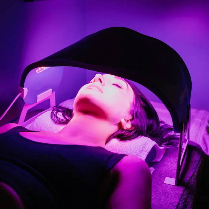Woman receiving red light therapy under a Celluma LED panel at sek Sauna Studio