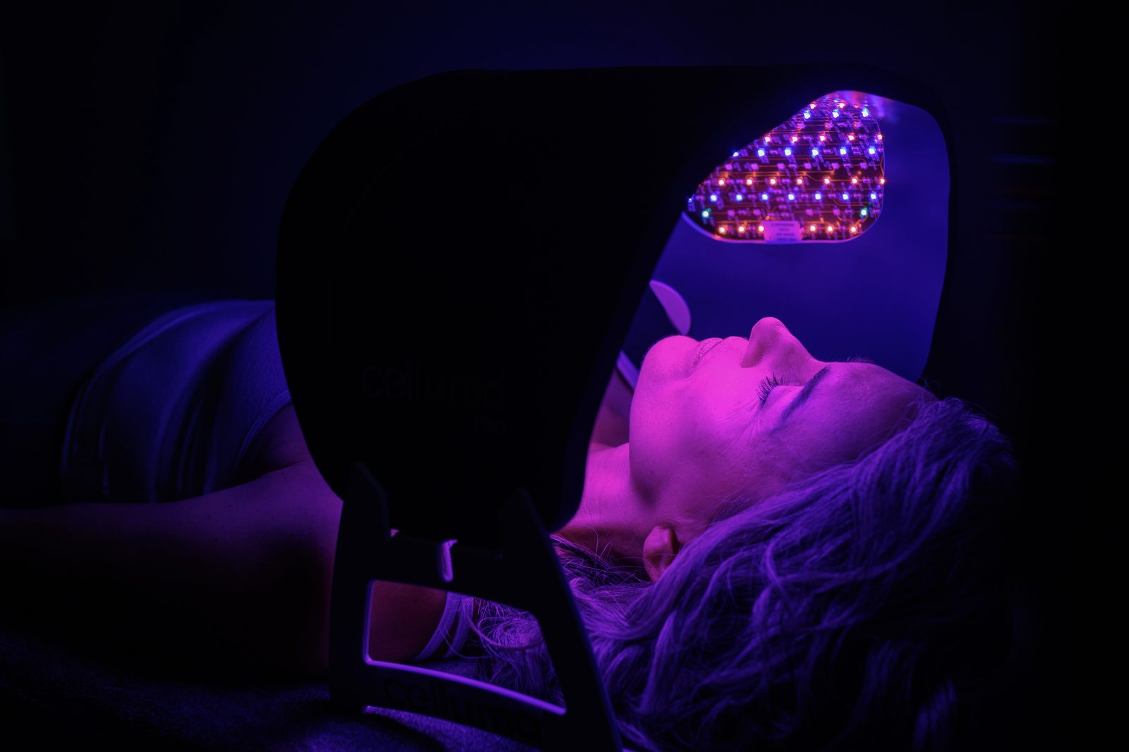 Guest under a Celluma PRO panel shaped over the face during a red light therapy session at sēk