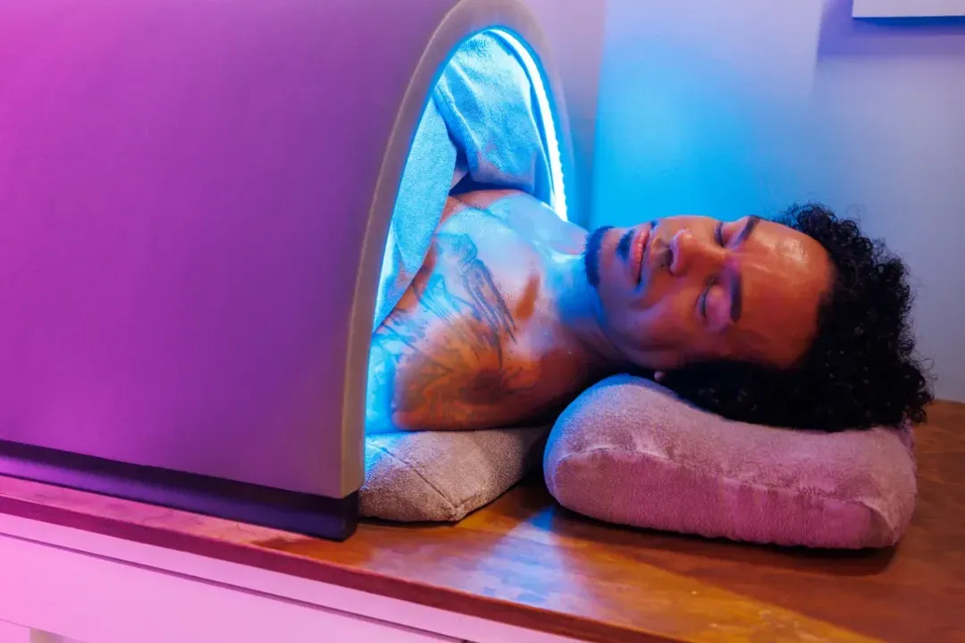 Guest resting with eyes closed in the Infrared Sauna Solo Pod at sēk Sauna Studio in Franklin, Tennessee, head comfortably outside the pod.