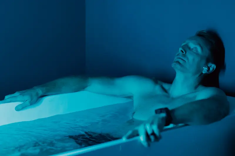 Client resting in the cold plunge under blue light at sēk Sauna Studio in Franklin, TN