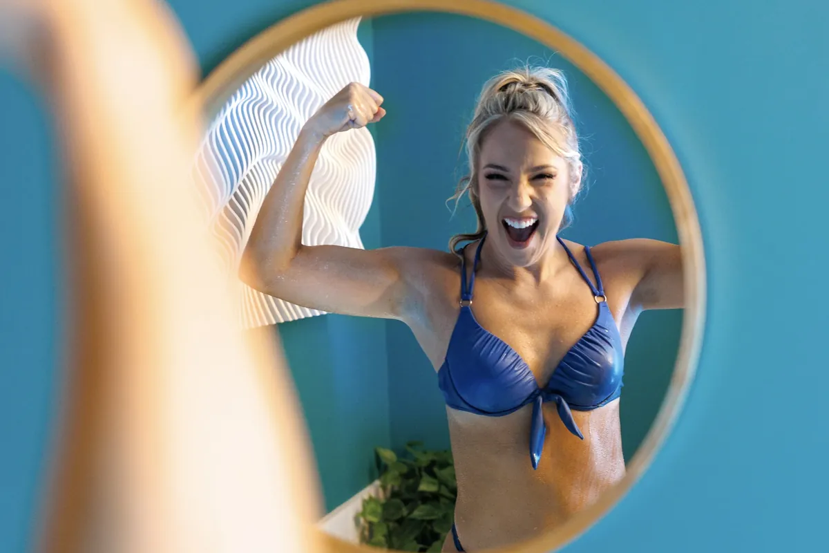 Guest flexing in the mirror after a cold plunge at sēk Sauna Studio