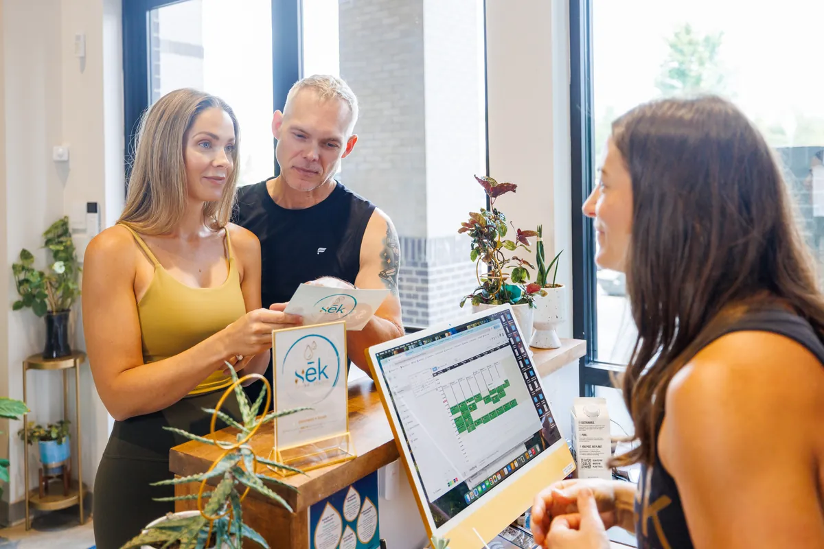 sēk team member walking two guests through membership options at the front desk