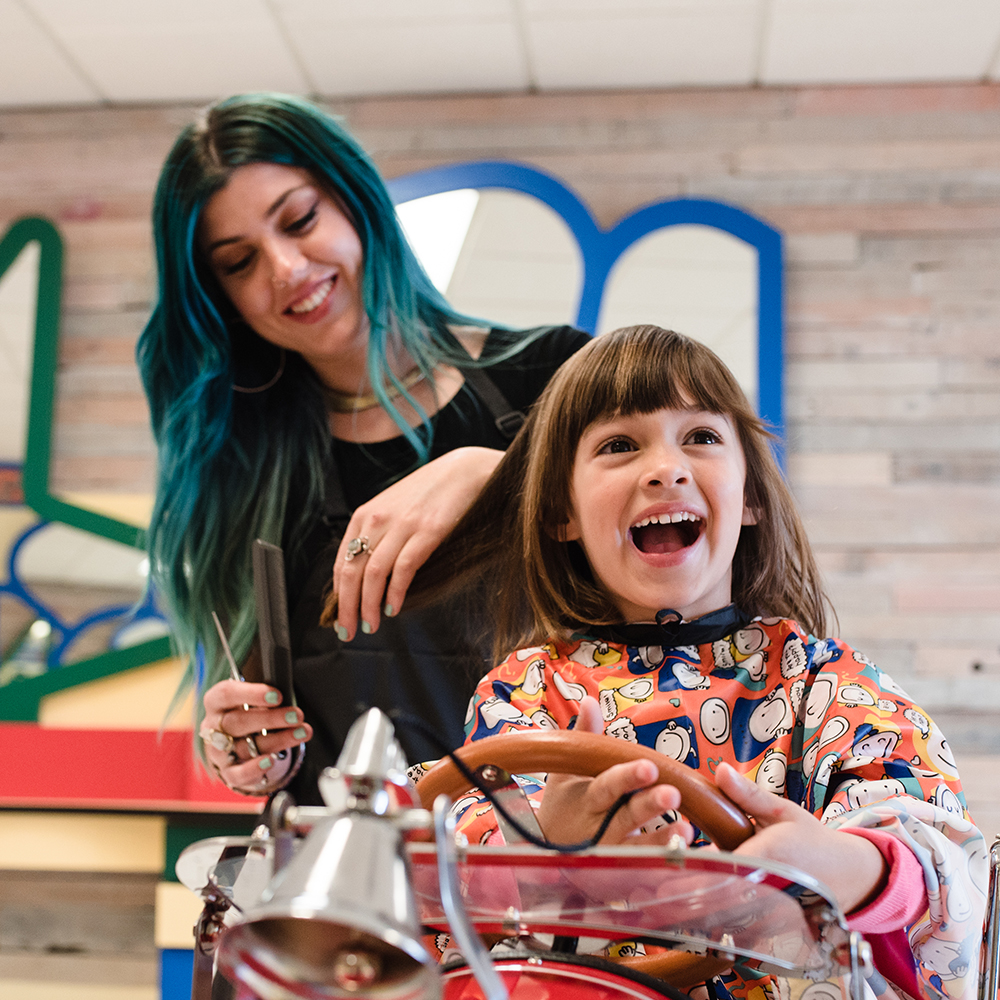 Photo of Stylist and child receiving haircut at Salon