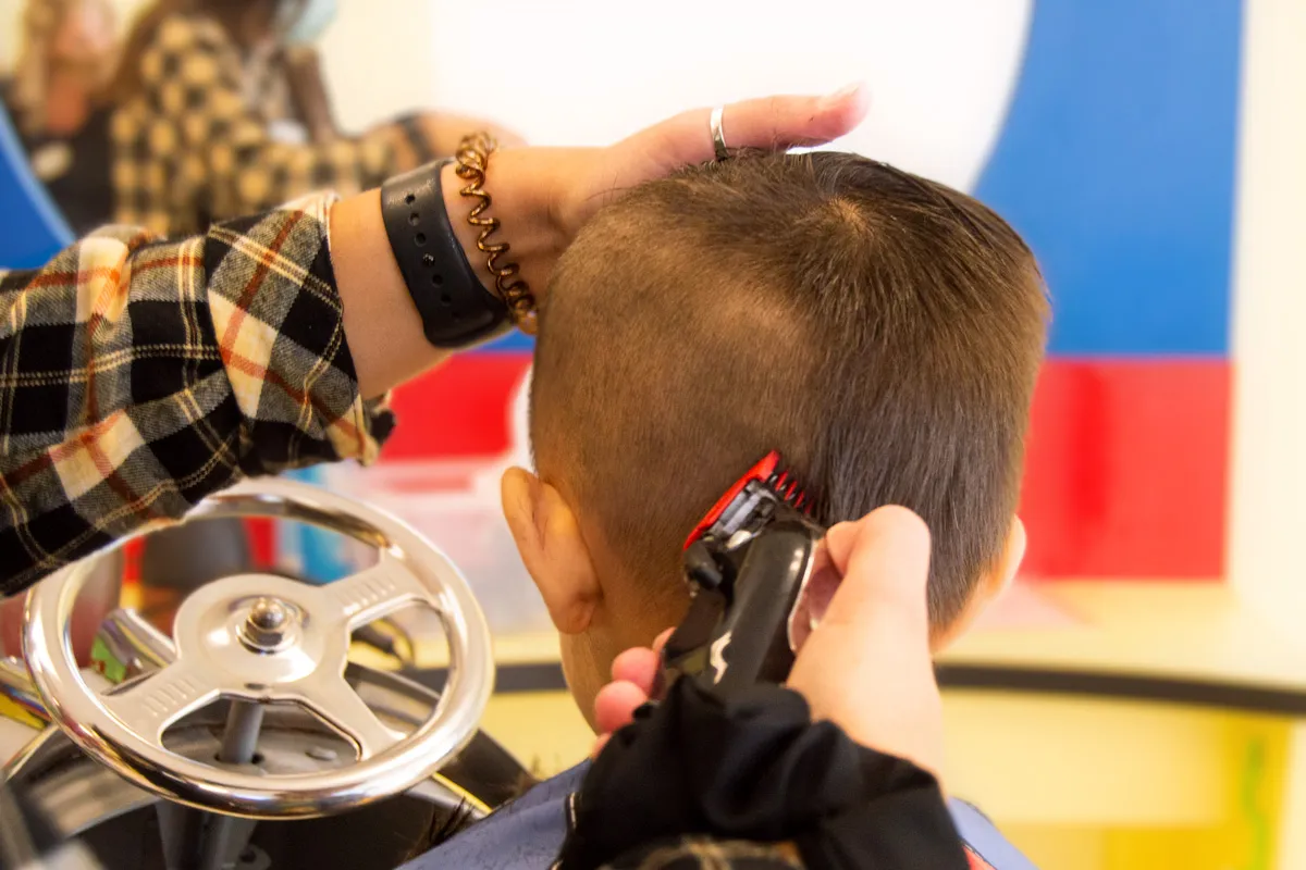 A little girl handing a balloon to a little boy in a Salon Chair
